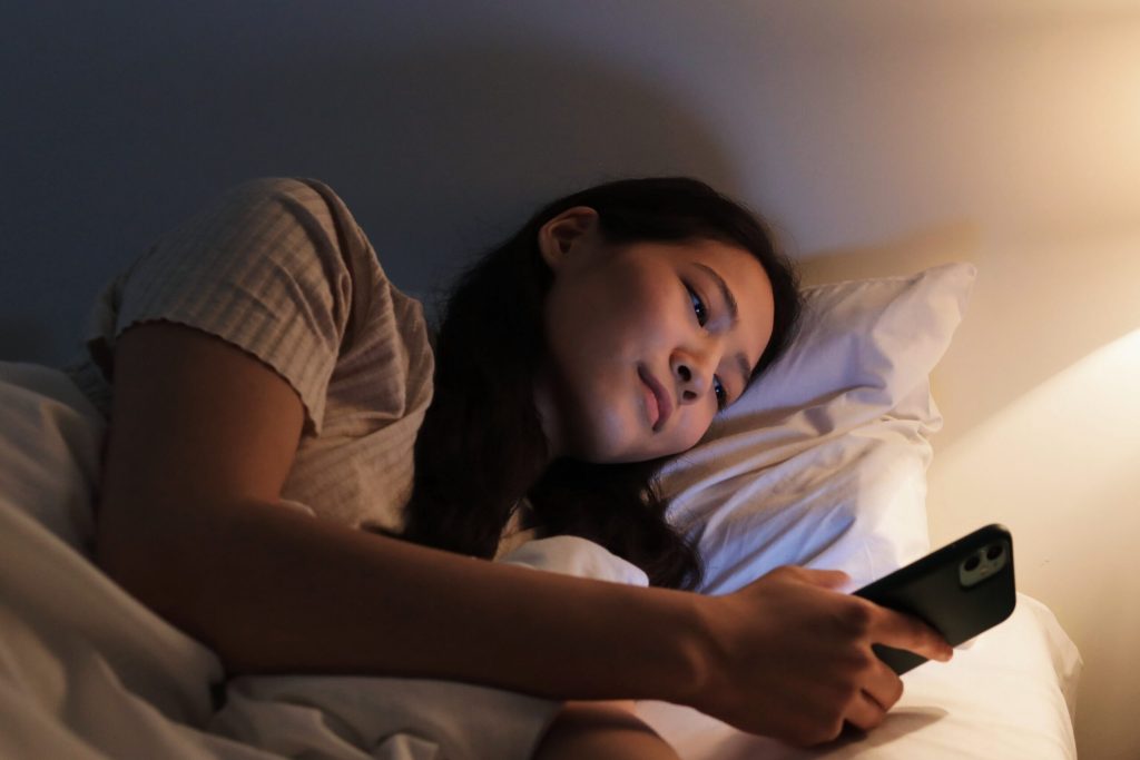 Wanita sedang scroll HP sebelum tidur di malam hari