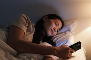 Wanita sedang scroll HP sebelum tidur di malam hari